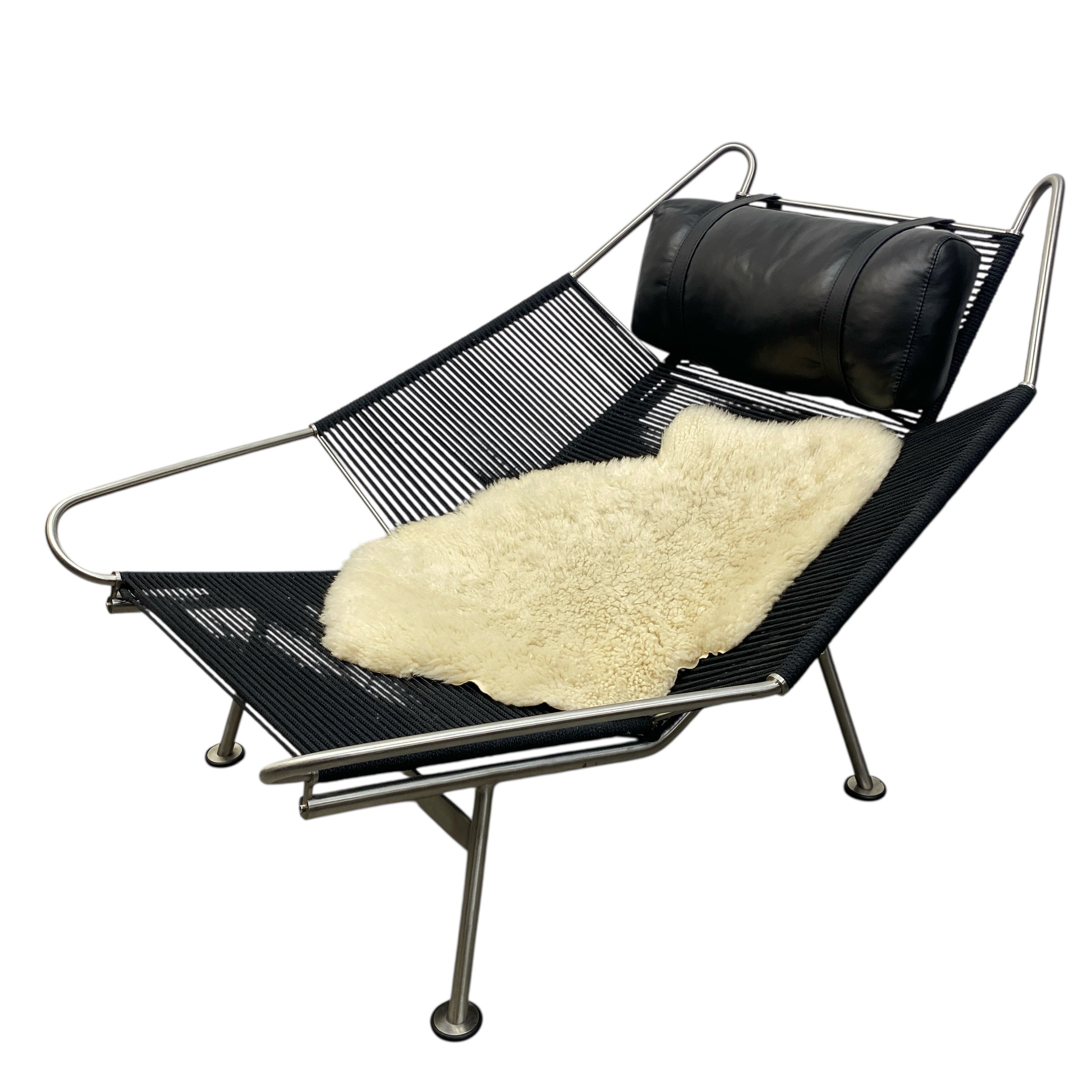 Black wire lounge chair with sheepskin rug and black cushion on a white background