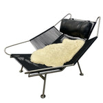 Load image into Gallery viewer, Black wire lounge chair with sheepskin rug and black cushion on a white background
