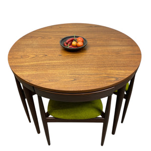Round wooden dining table with four chairs on a white background