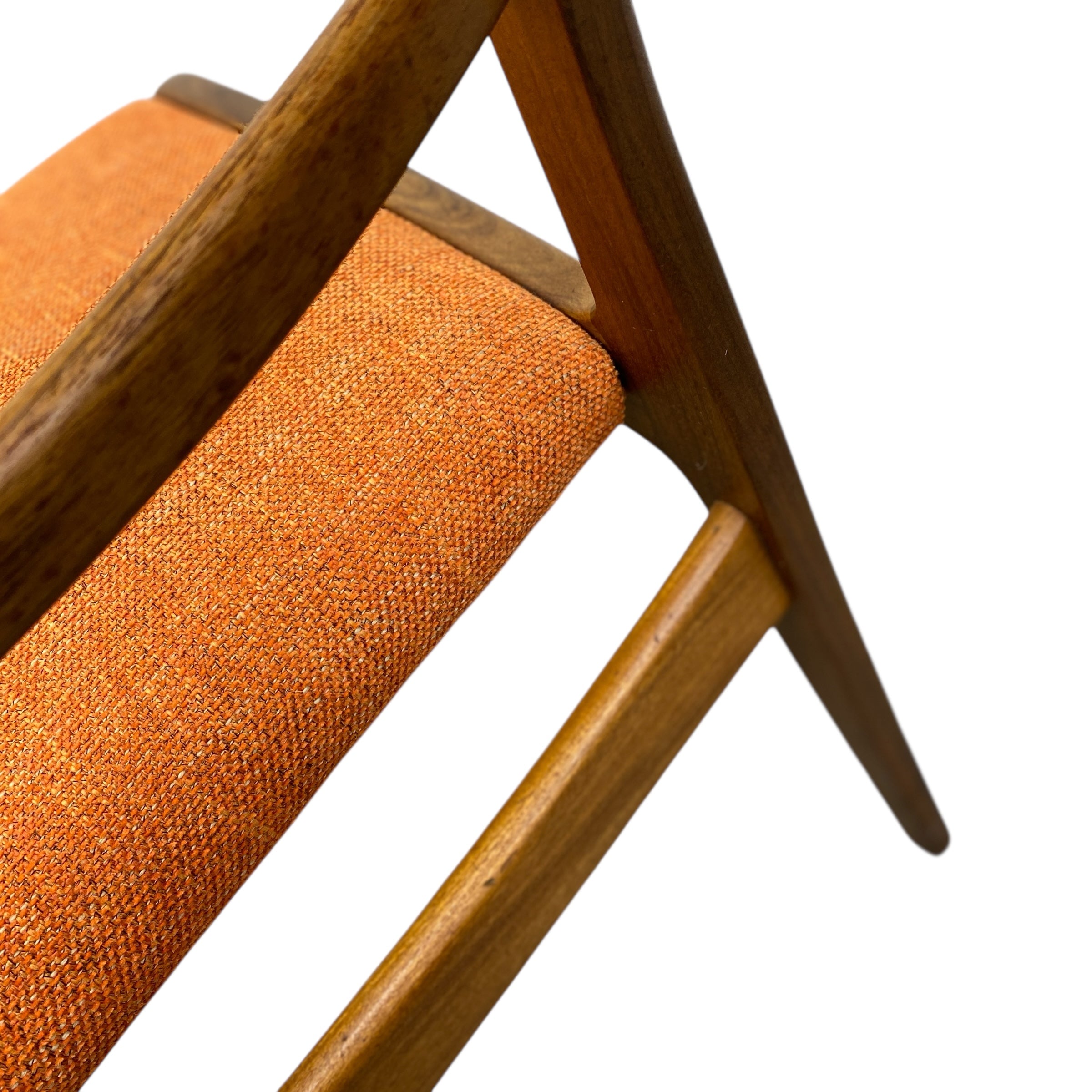 Close-up of an orange upholstered chair with wooden legs on a white background