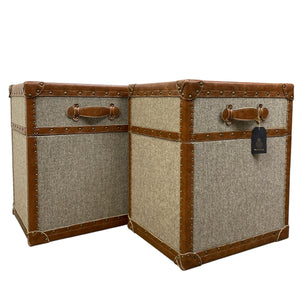 Two vintage-style trunks with brown leather accents on a white background