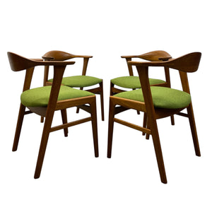 Four wooden chairs with green cushions on a white background