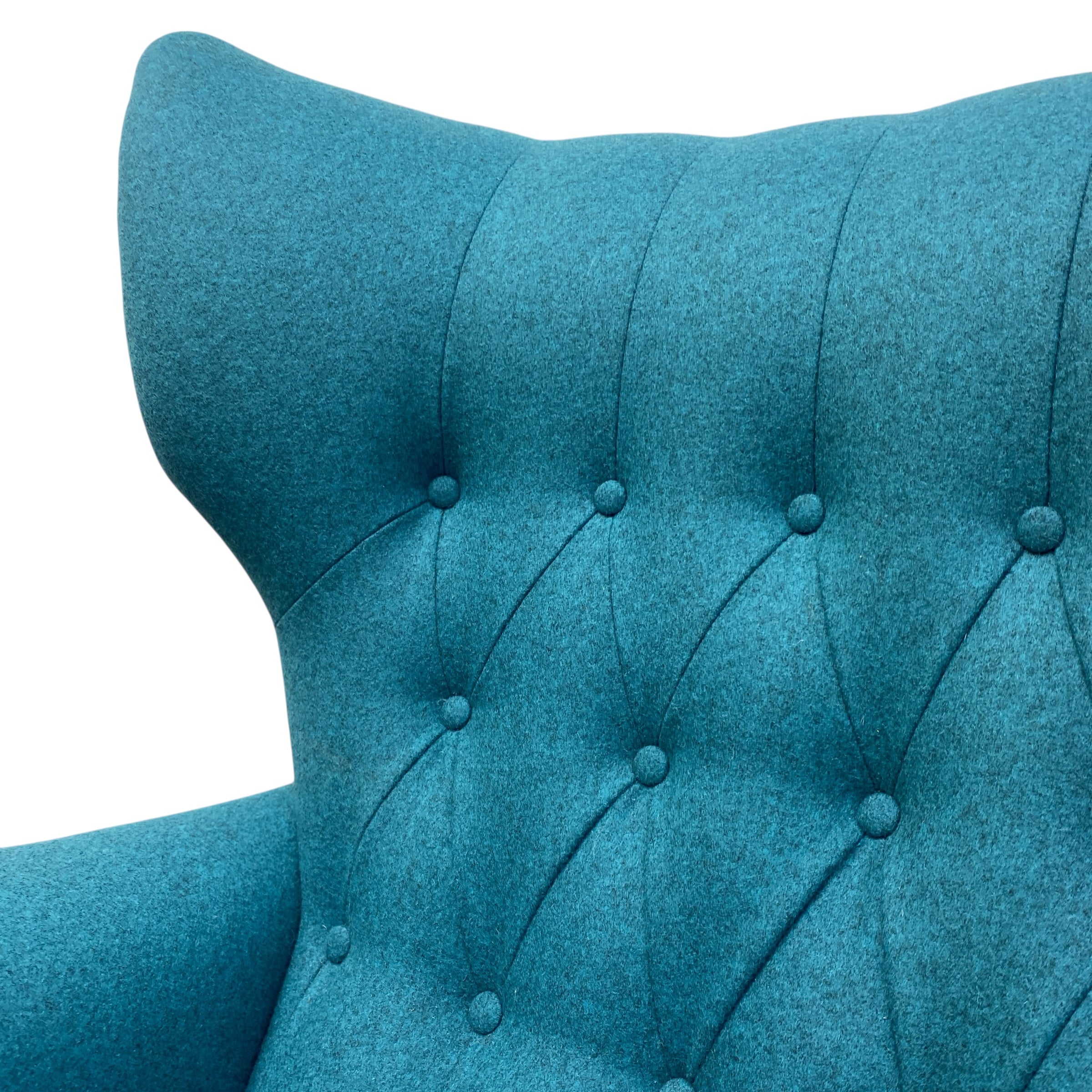 Close-up of a teal upholstered chair with buttoned backrest on a white background