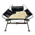 Load image into Gallery viewer, Modern lounge chair with black frame, leather cushion, and white fur blanket on a white background
