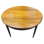 Load image into Gallery viewer, Round wooden table with dark legs on a white background
