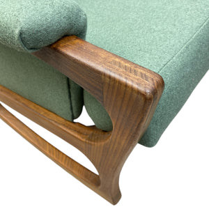 Close-up of a green upholstered chair with wooden armrests on a white background
