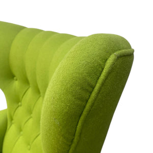 Close-up of a green upholstered chair with tufted detailing on a white background