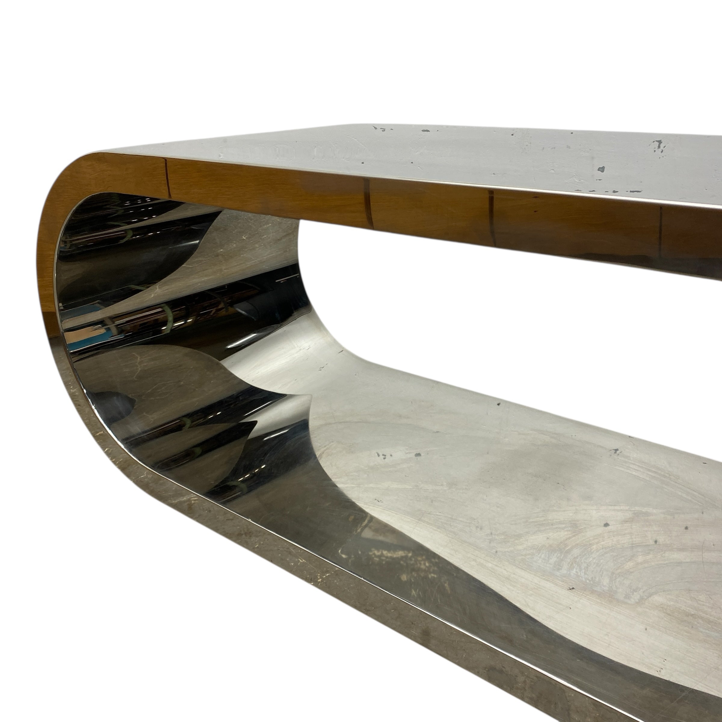 Modern, curved media table with a metallic finish on a white background