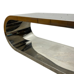 Modern, curved media table with a metallic finish on a white background