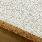 Load image into Gallery viewer, Close-up of a wooden formica surface with a textured white background
