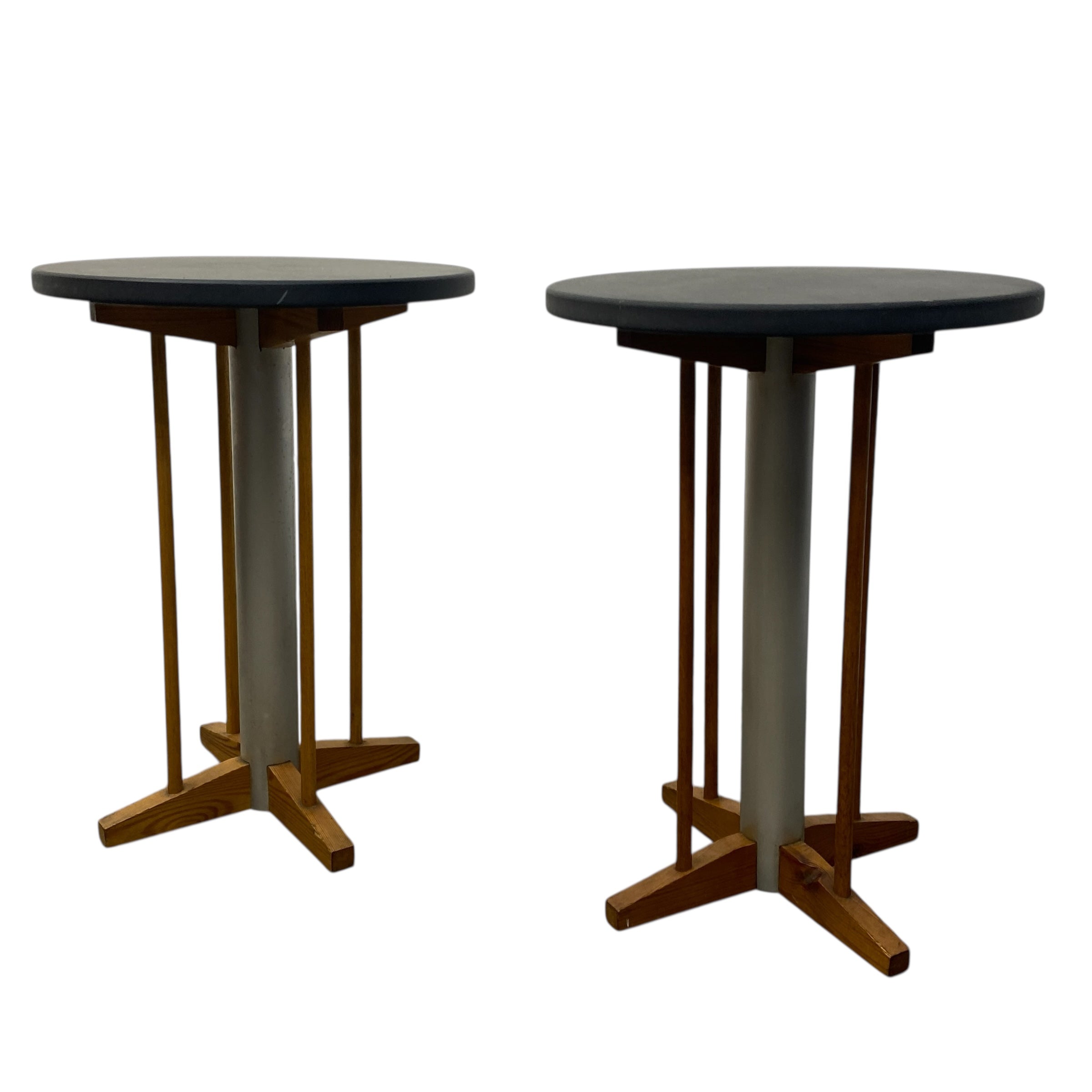 Two round tables with dark tops and wooden bases on a white background