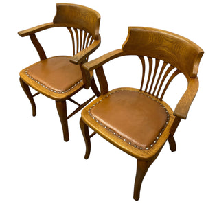 Two wooden chairs with brown leather seats on a white background