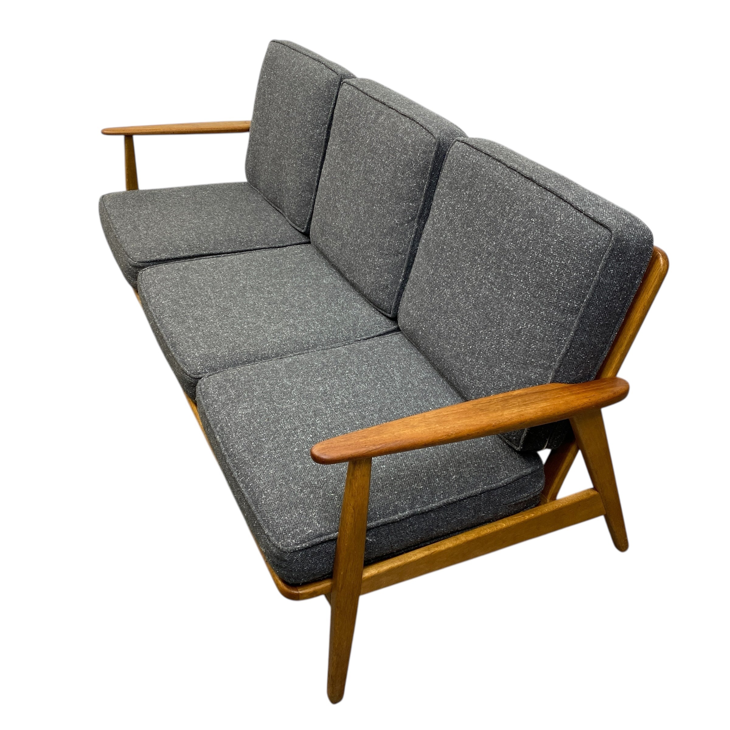 Grey cushioned sofa with wooden frame on a white background