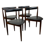 Load image into Gallery viewer, Set of four dark wood chairs with black leather seats on a white background

