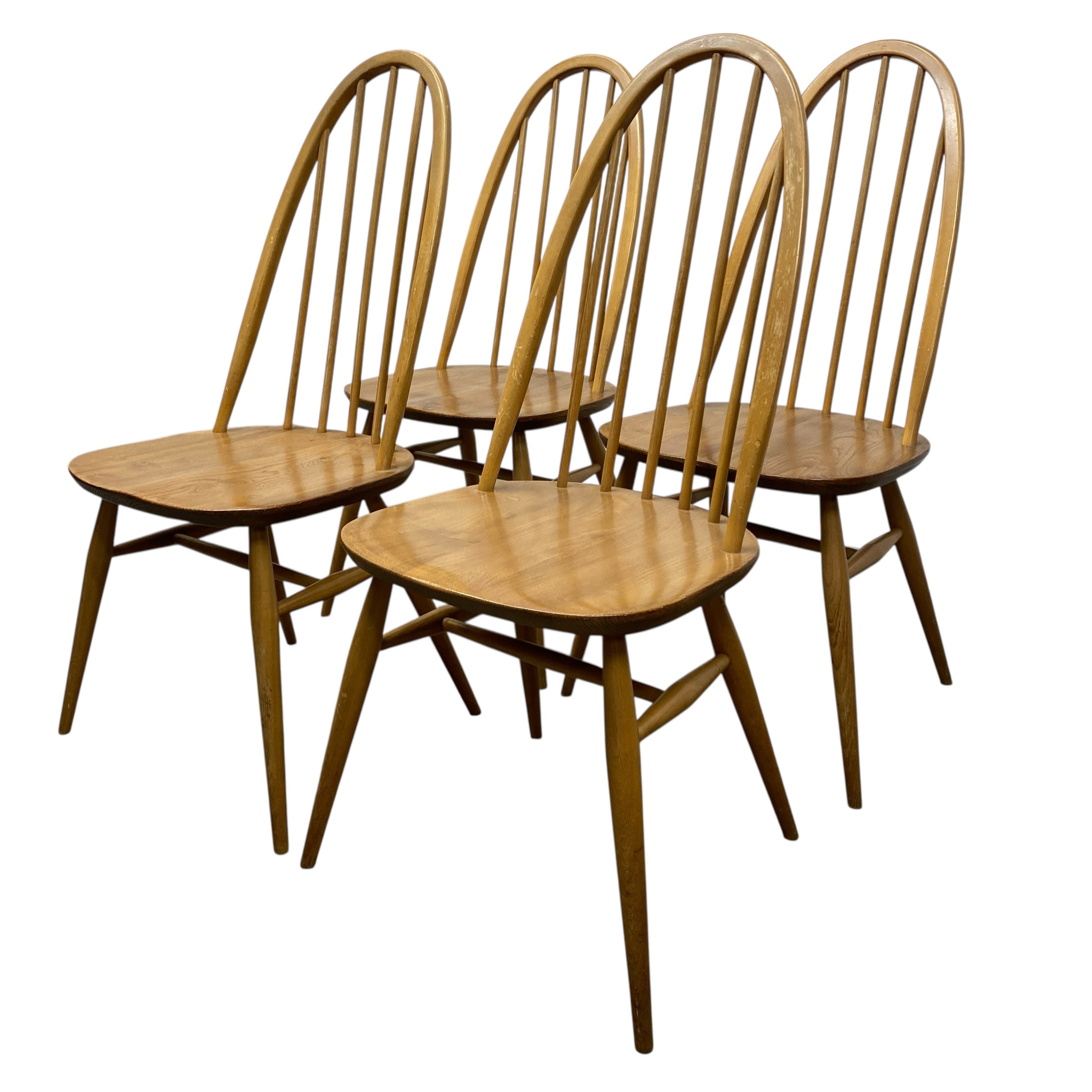 Four wooden chairs with spindle backs on a white background