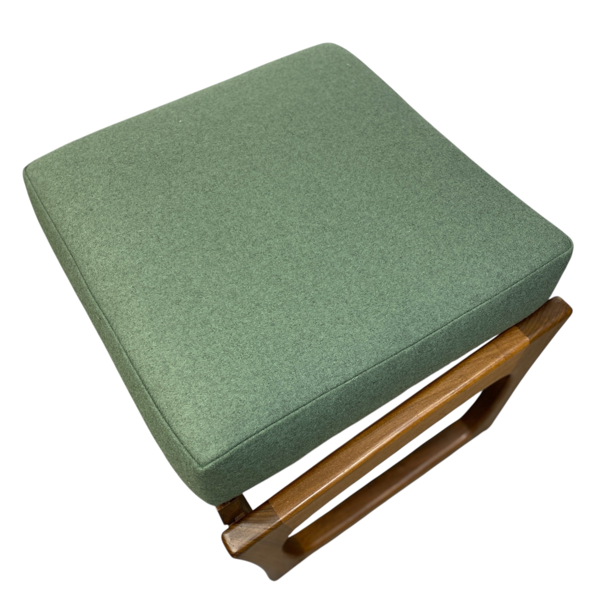 Green cushioned stool with wooden legs on a white background