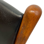 Load image into Gallery viewer, Close-up of a wooden armrest and black leather surface on a chair.
