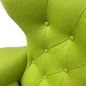 Close-up of a green upholstered chair with tufted backrest on a white background