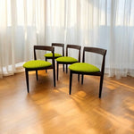 Load image into Gallery viewer, Four chairs with green cushions on a wooden floor in front of white curtains.
