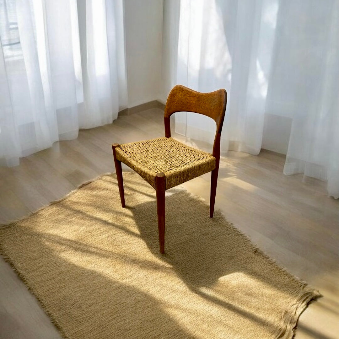 Wooden chair with woven seat on a rug in a room with white curtains