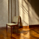 Load image into Gallery viewer, Wooden chair with patterned cushion against a textured wall with shadows.
