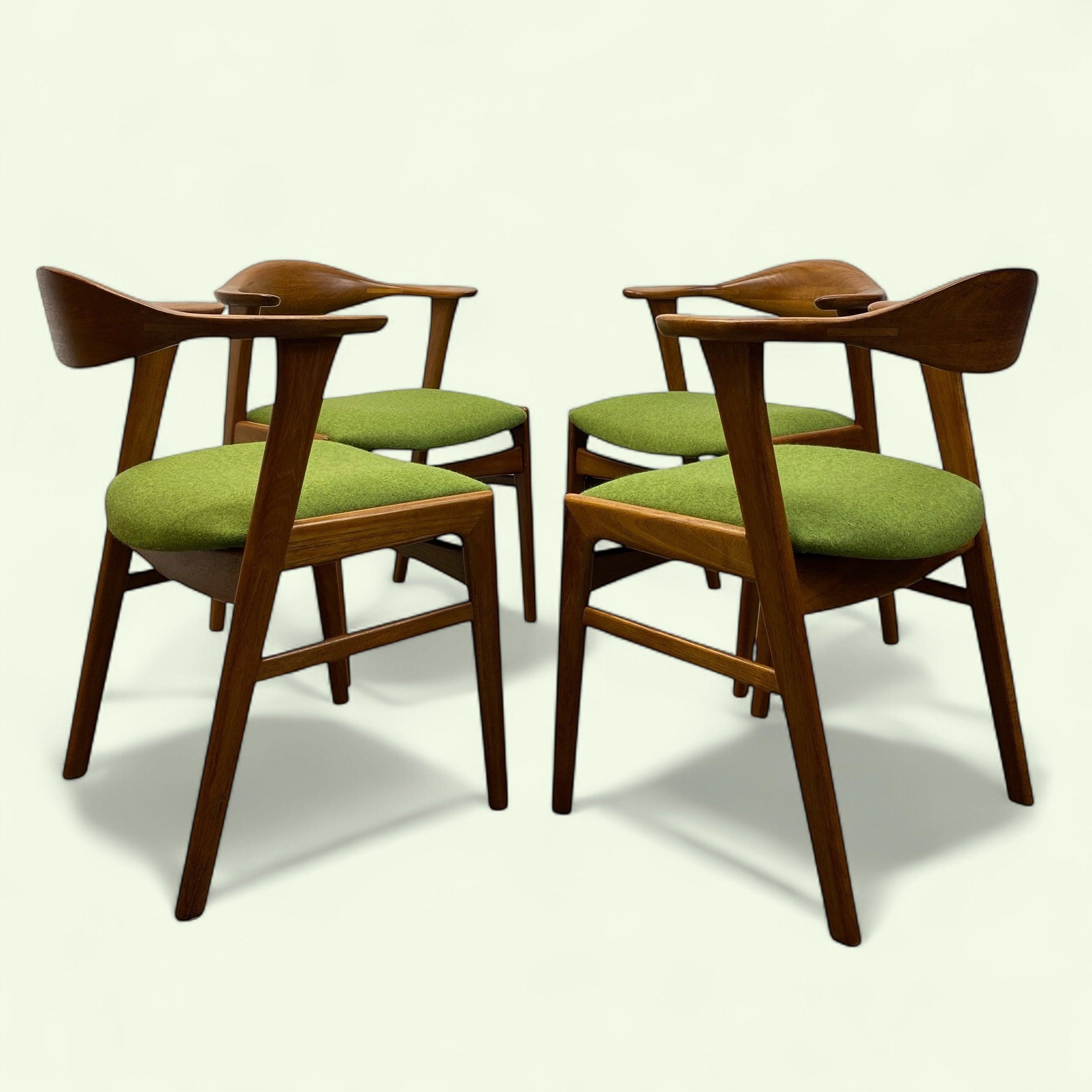 Danish Four wooden chairs with green cushions on a white background
