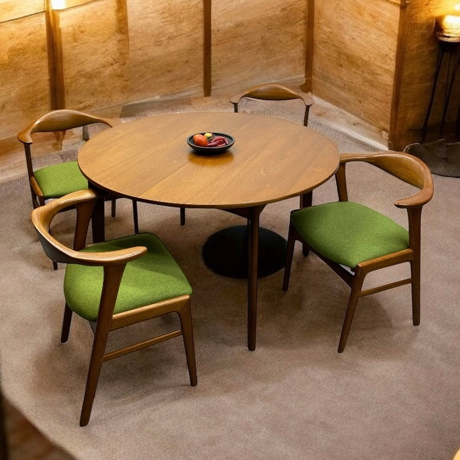 Round wooden table with four green cushioned chairs in a room with wooden walls.