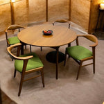 Load image into Gallery viewer, Round wooden table with four green cushioned chairs in a room with wooden walls.

