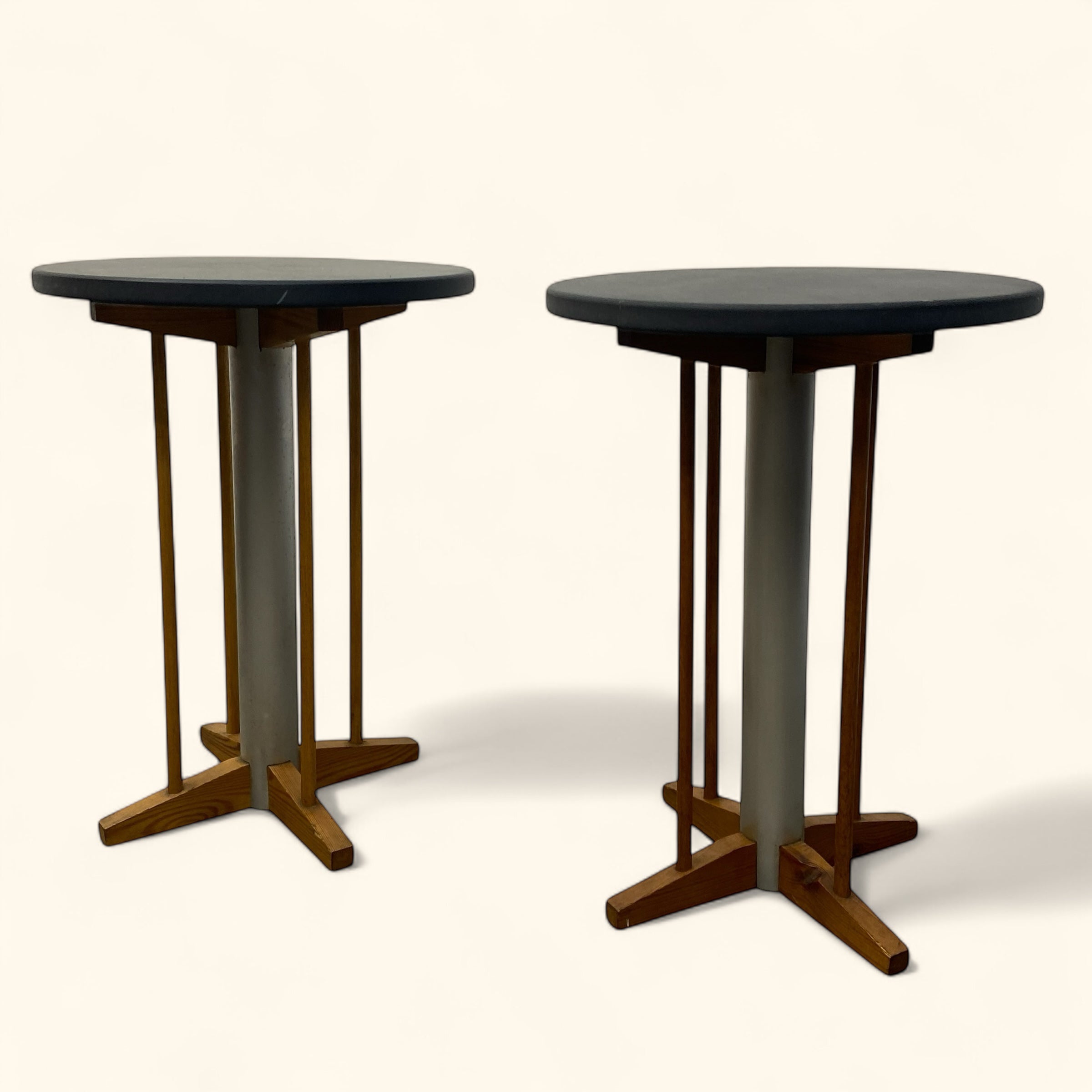 Two round tables with dark tops and wooden bases on a white background