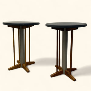 Two round tables with dark tops and wooden bases on a white background