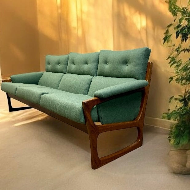 Green sofa with wooden frame in a room with a plant