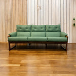 Load image into Gallery viewer, Green sofa on a wooden floor with a wooden wall background
