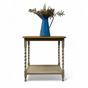 Wooden side table with a blue vase and floral arrangement on a white background
