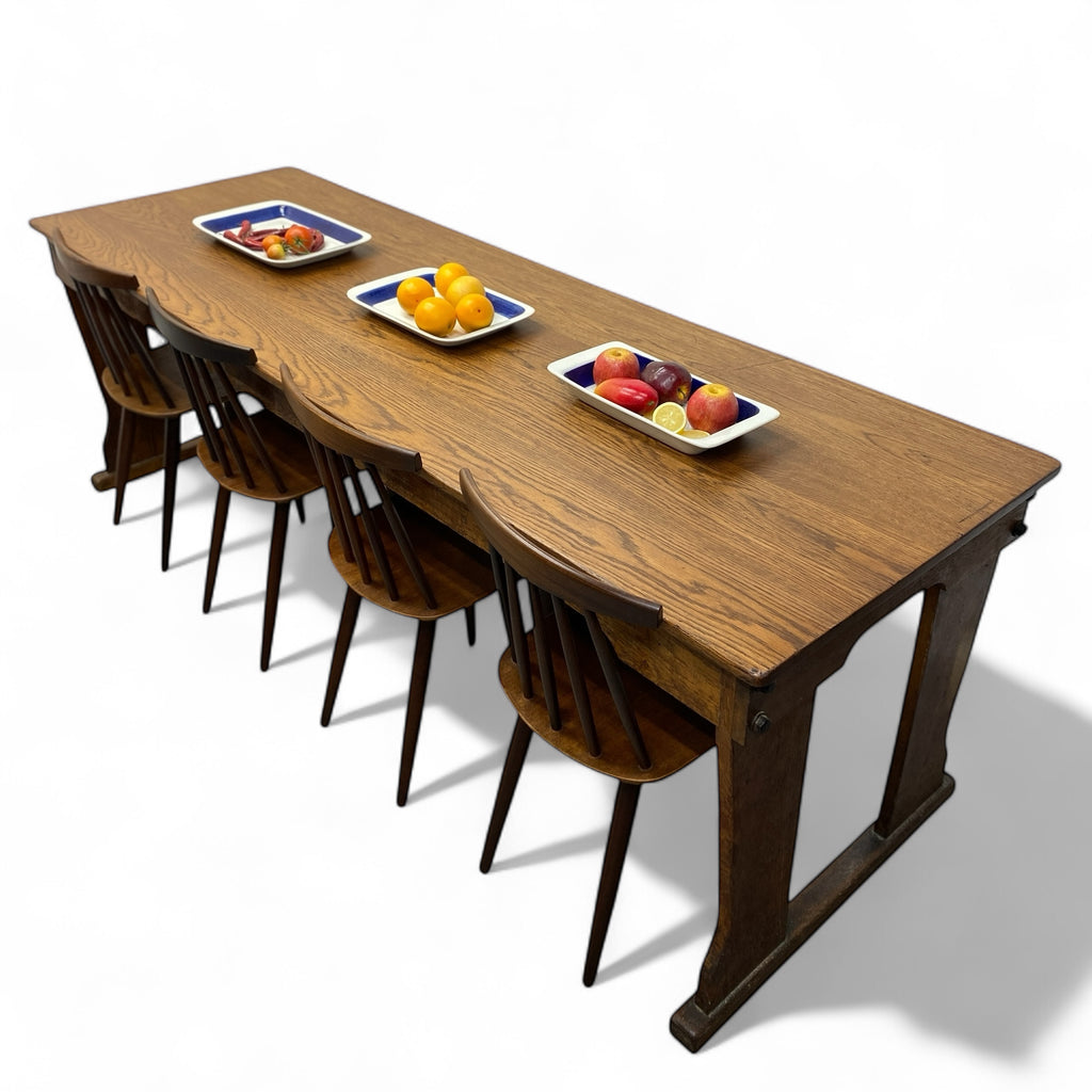 Wooden dining table with four chairs and fruit plates on a white background