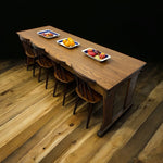 Load image into Gallery viewer, Long wooden dining table with chairs on a wooden floor
