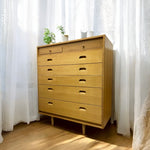 Load image into Gallery viewer, Wooden dresser with multiple drawers in a room with white curtains.
