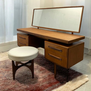 Wooden vanity desk with mirror and stool on a patterned rug