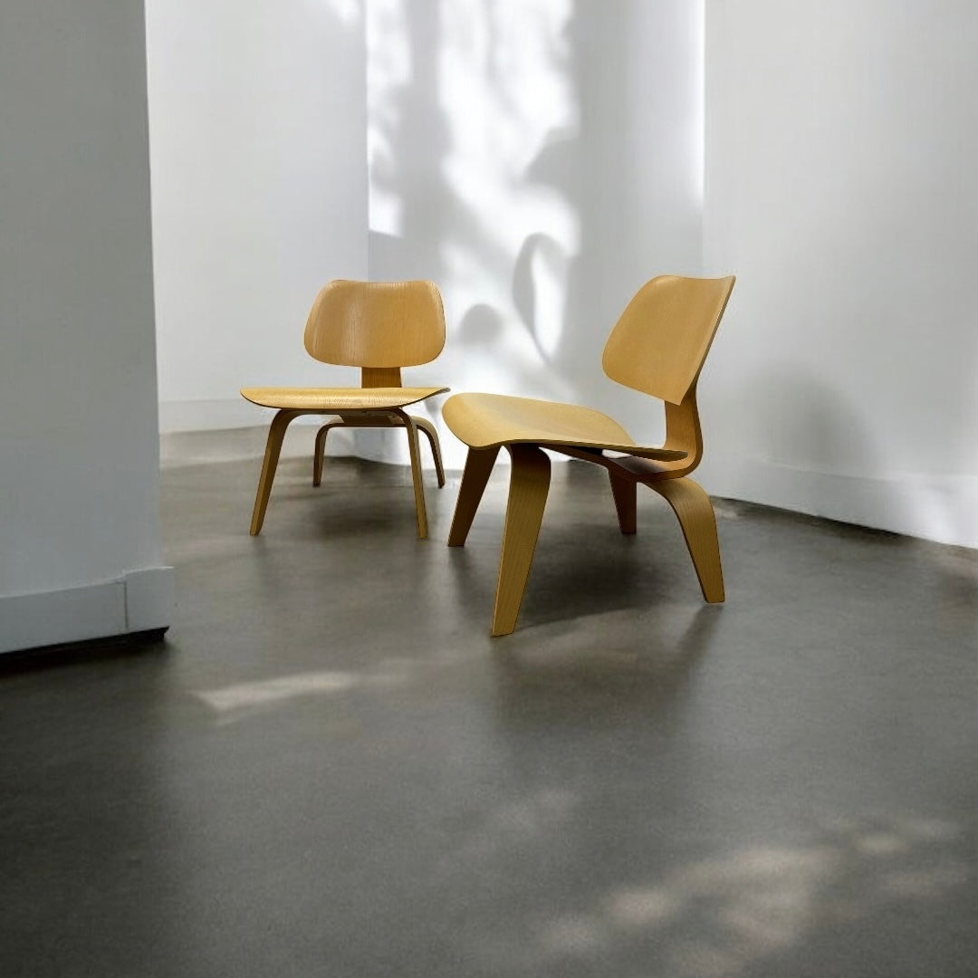 Two wooden chairs on a concrete floor with a white wall in the background