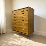 Load image into Gallery viewer, Wooden dresser with multiple drawers in a room with light-colored walls and carpet.
