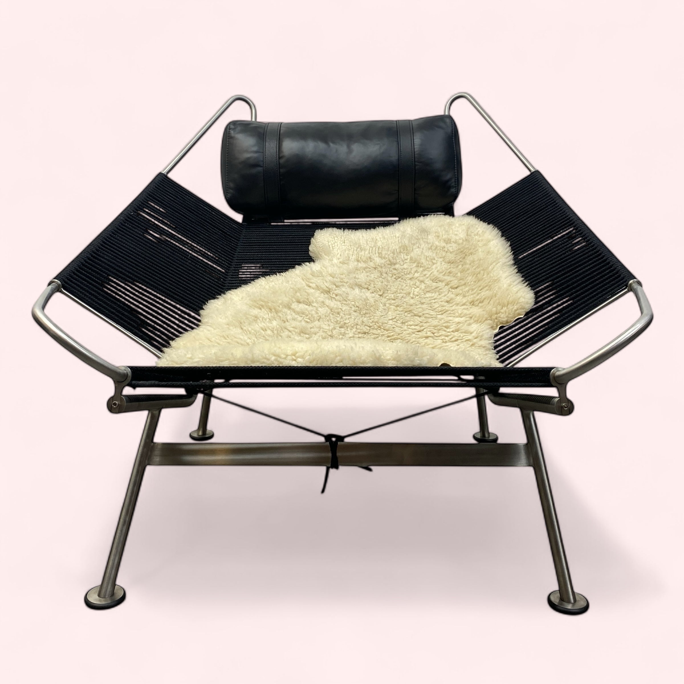 Modern black lounge chair with a white fur throw on a white background
