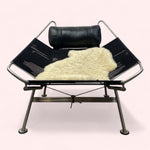 Load image into Gallery viewer, Modern black lounge chair with a white fur throw on a white background
