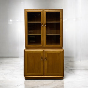 Wooden cabinet with glass doors on a white marble floor and wall.