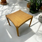 Load image into Gallery viewer, Wooden table with woven surface on a light-colored floor with plants in the background
