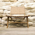 Load image into Gallery viewer, Woven chair against a stone wall
