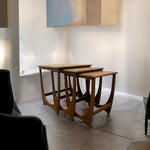 Load image into Gallery viewer, Set of three wooden nesting tables in a minimalistic room.
