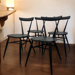 Load image into Gallery viewer, Four black chairs arranged on a wooden floor against a white wall.
