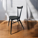 Load image into Gallery viewer, Black chair on a wooden floor with a white wall background
