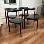Load image into Gallery viewer, Four dark wooden chairs with black seats on a wooden floor.
