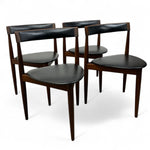 Load image into Gallery viewer, Set of four dark wood chairs with black leather seats on a white background
