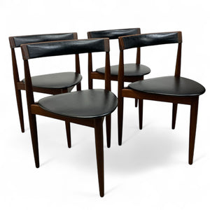 Set of four dark wood chairs with black leather seats on a white background